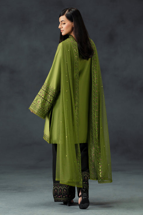Woman wearing a green embroidered outfit with a dark background